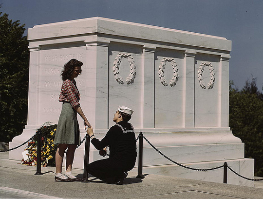 girl wearing a pencil skirt as soldier kneels before her