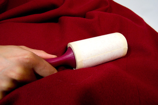 a lint brush being used on a red coat