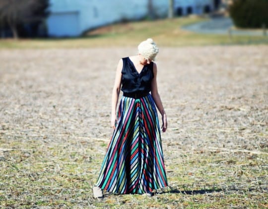 a young woman wearing a vintage skirt modeling in a field.