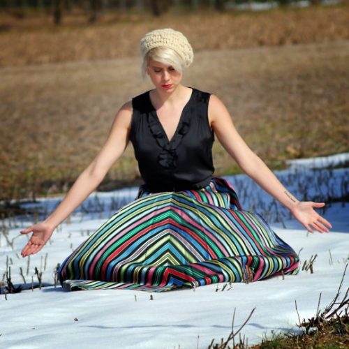 a woman wears a vintage striped skirt in a field