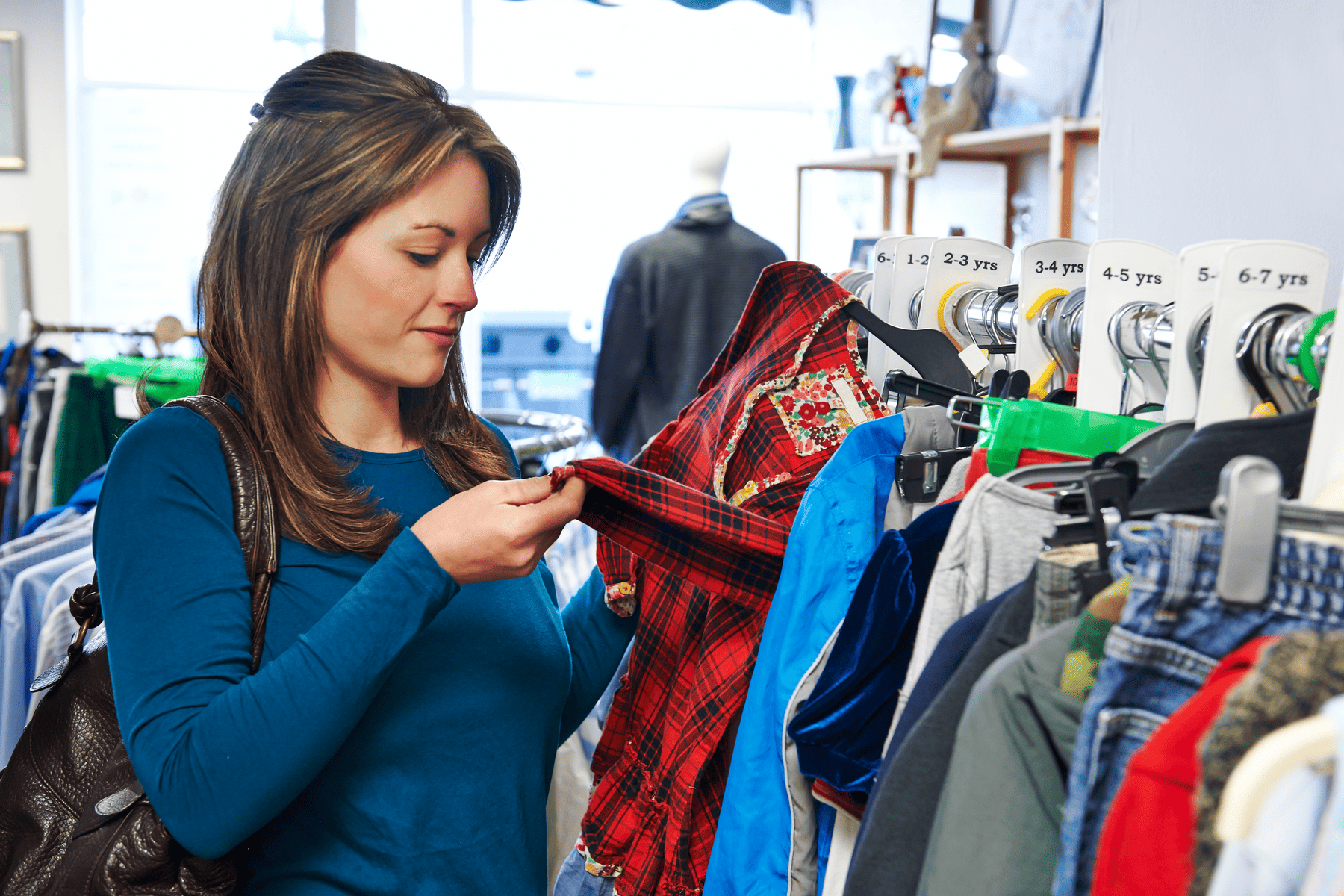 Woman inspecting vintage clothes at a thrift store