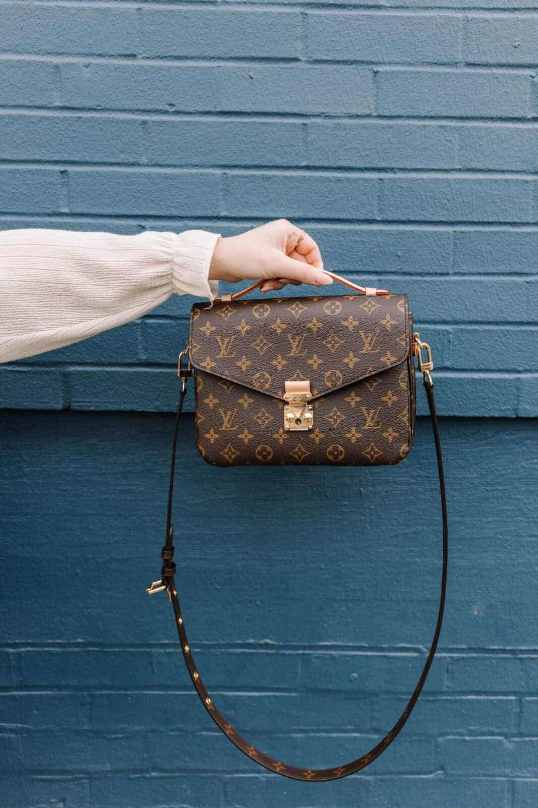 person holding brown leather sling bag